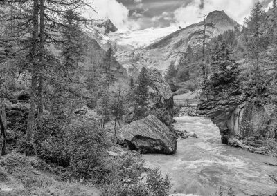 Gebirgsszene mit Wald und Bach in Schwarz-Weiß